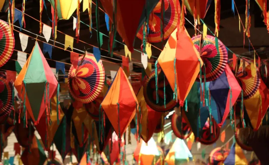 Diversas lanternas de papel coloridas penduradas em cordas como decoração de São João para loja, criando um ambiente festivo e alegre com padrões e cores vivas.
