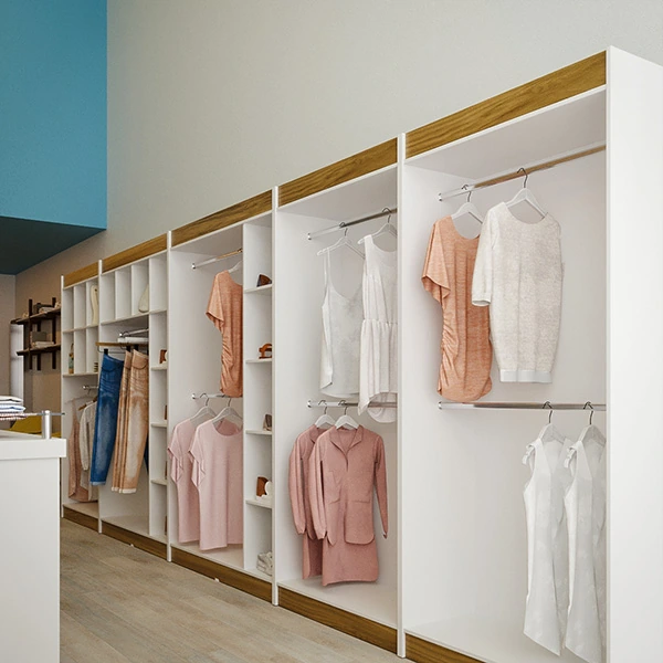 A imagem mostra uma perspectiva focada na parede direita da mesma loja de roupa pequena e simples descrita anteriormente. A decoração se caracteriza pela presença de araras de roupas dispostas verticalmente, cada uma com peças cuidadosamente selecionadas e espaçadas. As araras são fixadas em nichos brancos que contrastam com a parede de tom neutro, realçando as roupas em tons pastel. 