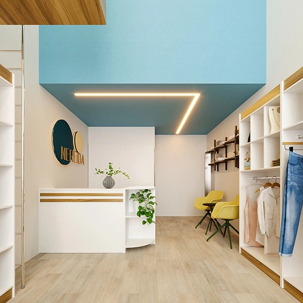  A imagem captura o fundo de uma loja de roupa pequena e simples, detalhando a área do balcão de caixa e o espaço do provador. O balcão branco com detalhes em madeira oferece uma recepção minimalista, enquanto o logotipo da marca é elegantemente exibido na parede, criando um ponto focal. Uma planta em um vaso decorativo adiciona um toque de verde e vida ao espaço. Ao lado, duas cadeiras amarelas sugerem um local de espera confortável junto ao provador.