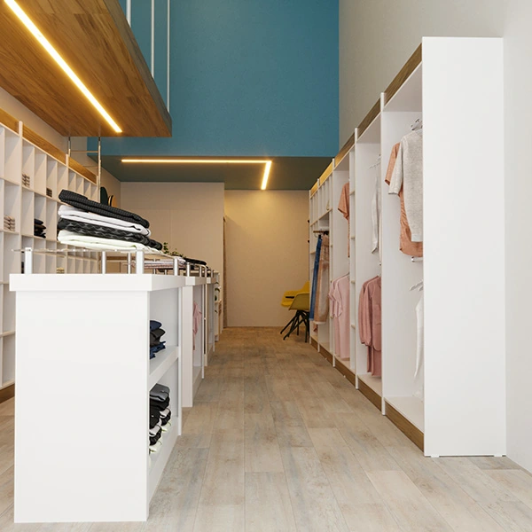 É a mesma imagem que a foto anterior, porém o ângulo é diferente. Nesse caso a câmera está mais próxima do chão e dos móveis à direita da imagem acima, logo ao lado do balcão branco e das araras com algumas camisas de clores claras como rosa e branco penduradas.