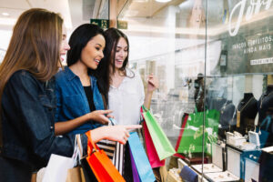 mulheres com sacolas de compras olhando para uma vitrine